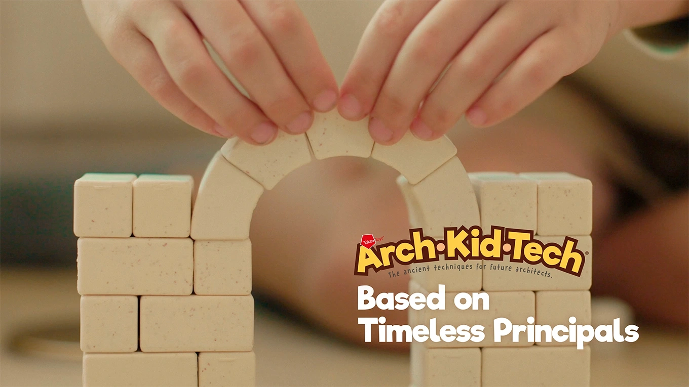 Child placing the keystone to complete a Roman arch structure with Arch-Kid-Tech®, demonstrating how alignment and compression bring stability.