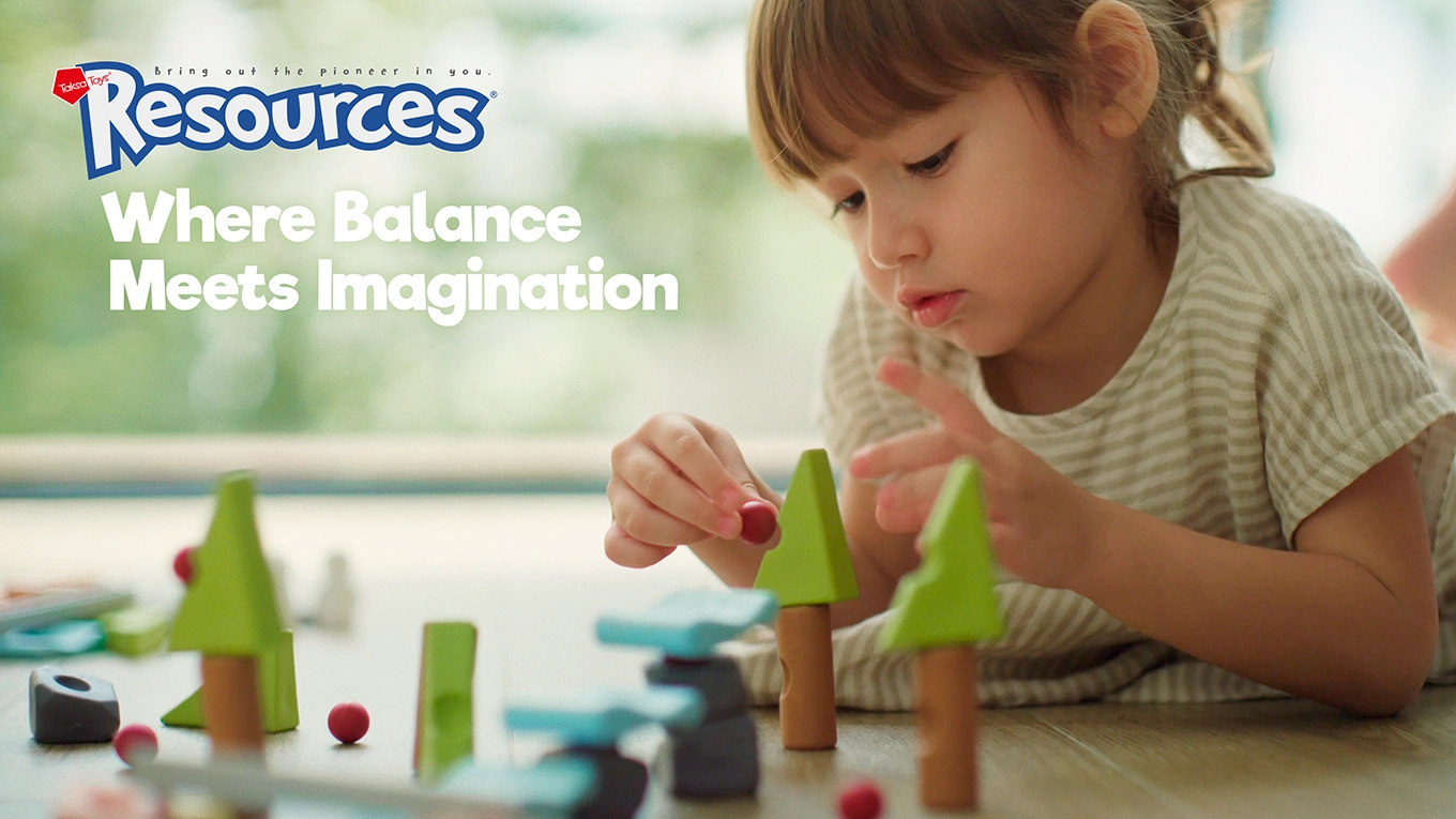 Child carefully placing pieces to build a balanced structure with Resources®, exploring stability through placement and adjustment.